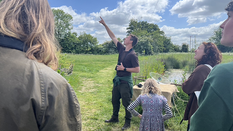 Group of people on farm walk with Harry Read who is pointing to something in thee sky