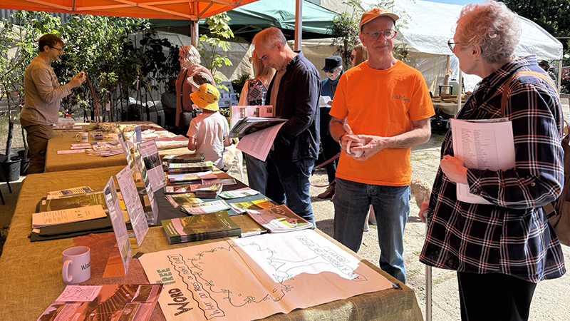 The ORC stand at Wakelyns. with people standing around under a gazebo looking at literature and talking.