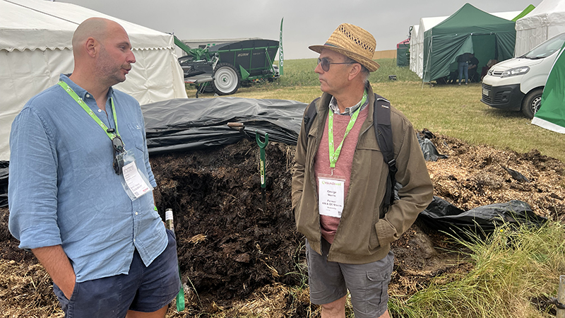 Two men standing in front of a pile of manure talking Bokashi