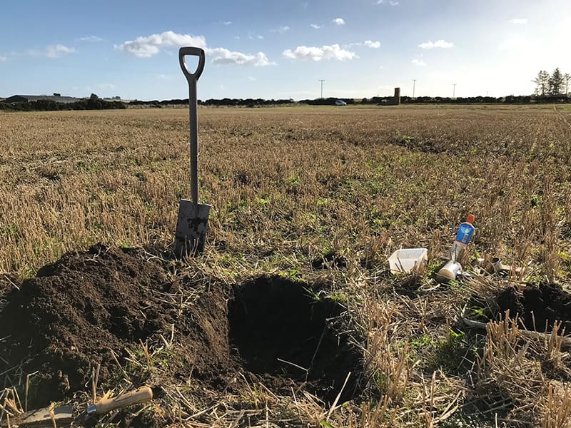 Soil pit in field with spade and soil samples