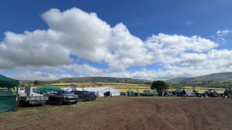 View over Royal Welsh Grassland Event site with exhibitor tents a muddy field and hills in the background