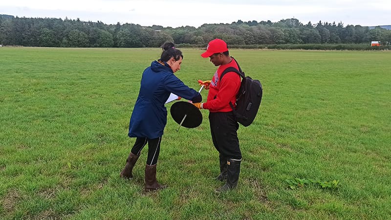 A man and a woman in a field with a plate meter