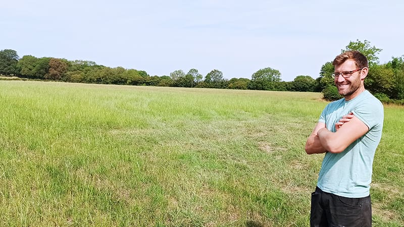 Man standing in field of grass with arms folded