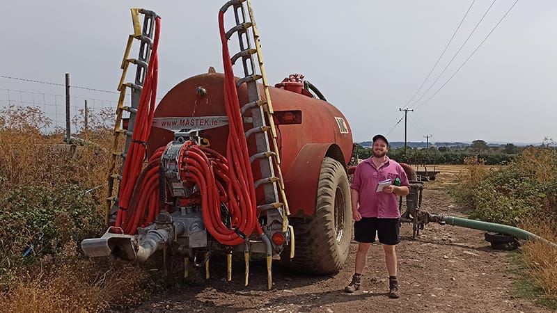 Man stands next to a slurry spreader
